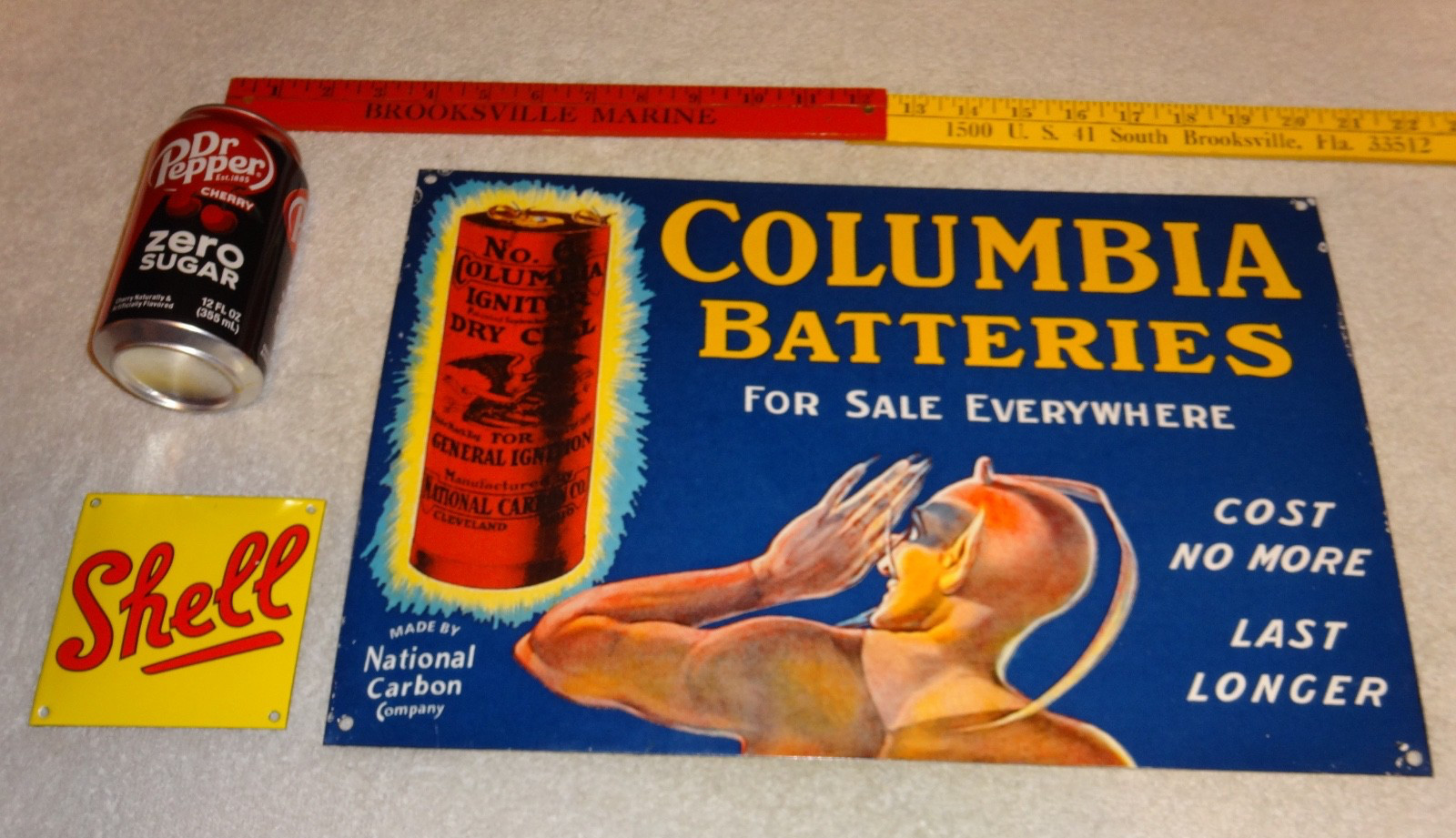 VINTAGE COLUMBIA DRY CELL BATTERIES +DEVIL 16″ PORCELAIN METAL GASOLINE OIL SIGN